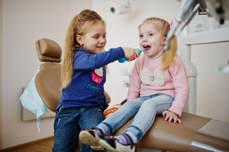 Two cutie little baby girls at dentist chair. Children dental.